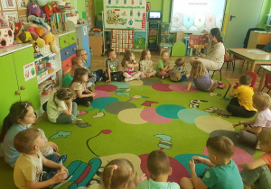 Dzieci z zainteresowaniem słuchają bajki czytanej przez mamę Mikołaja.