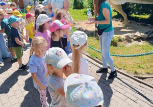 Dzieci zwiedzają park z dinozaurami.