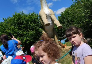 Dzieci zwiedzają park z dinozaurami.