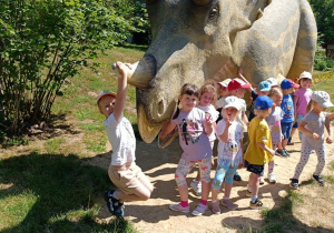 Dzieci zwiedzają park z dinozaurami.