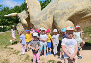 Dzieci zwiedzają park z dinozaurami.