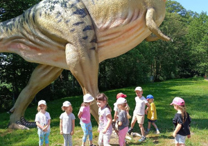 Dzieci zwiedzają park z dinozaurami.