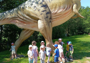 Dzieci zwiedzają park z dinozaurami.