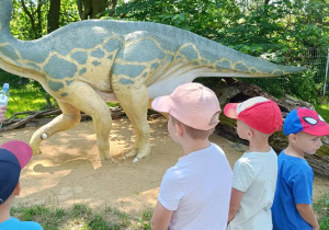 Dzieci zwiedzają park z dinozaurami.