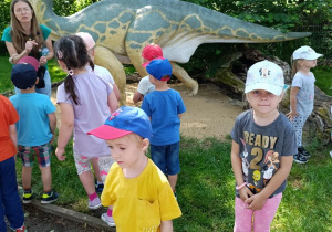 Dzieci zwiedzają park z dinozaurami.