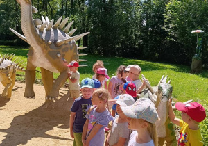 Dzieci zwiedzają park z dinozaurami.