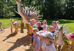 Dzieci zwiedzają park z dinozaurami.