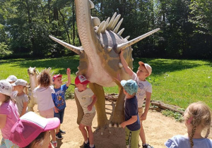 Dzieci zwiedzają park z dinozaurami.