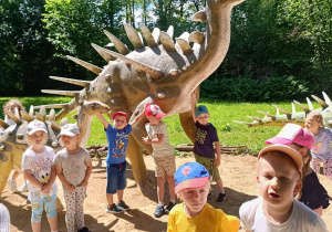 Dzieci zwiedzają park z dinozaurami.