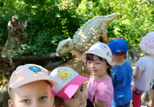 Dzieci zwiedzają park z dinozaurami.