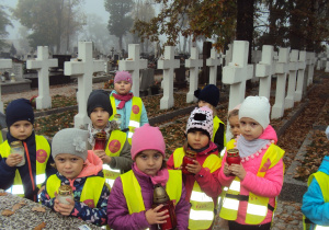 Dzieci z grupy "Kreciki" zapalają znicze na kutnowskim cmentarzu