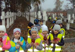 Dzieci z grupy "Żabki" zapalają znicze na kutnowskim cmentarzu