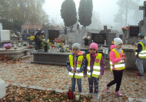 Amelka, zuzia i Emilka stawiają znicze na grobach nieznanych żołnierzy