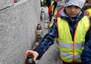 Dzieci zapalają znicze przy pomniku