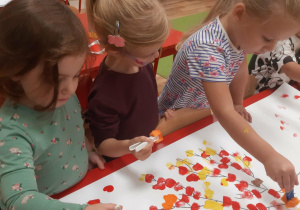 Hania, Pola i Roksana odciskają liście z gąbki w kolorach jesiennych.