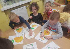 Dzieci wyklejają kontur gruszki plasteliną.