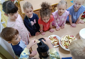 Dzieci wykonują sok przy użyciu wyciskarki.