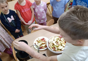 Dzieci wykonują sok przy użyciu wyciskarki.