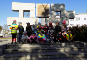 Zdjęcie grupowe dzieci ze zniczami przed pomnikiem Harcerzy