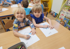 Alina i Apolonia malują kontur swojej rączki.