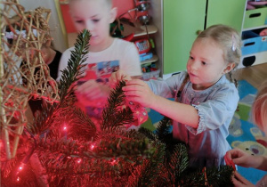 Dzieci ubierają choinkę.