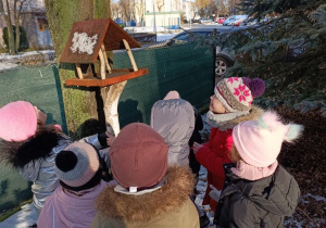 Dzieci oglądają karmniki w przedszkolnym ogrodzie