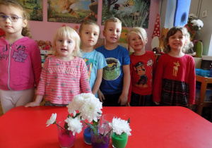 Lena, Klara, Filip, Eryk Hubert i Lilly prezentują swoje kwiatki w kolorowej wodzie.