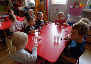 Lilianka, Marcel, Filip, Lena, Marysia i Eryk przy pomocy łyżek grają na szklankach.