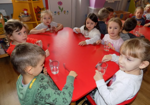 Piotrek, Lilly, Gabrysia, Marta, Nadia i Zosia przy pomocy łyżek grają na szklankach.