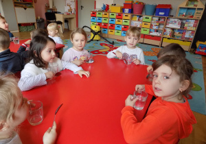 Gabrysia, Marta, Nadia, Zosia i Lilly przy pomocy łyżek grają na szklankach.