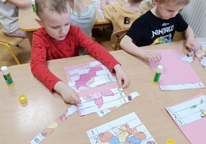 Dzieci układają puzzle "Kubuś Puchatek i przyjaciele" z 9 części..