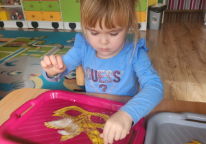 Julia.B nakleja piórka do swojej maski.
