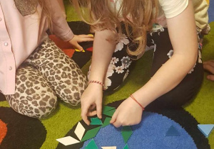 Dzieci układają kompozycje kwiatowe z mozaiki geometrycznej.