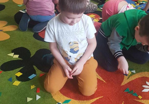 Dzieci układają kompozycje kwiatowe z mozaiki geometrycznej.