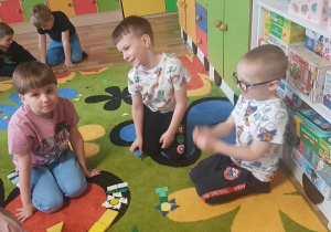 Dzieci układają kompozycje kwiatowe z mozaiki geometrycznej.