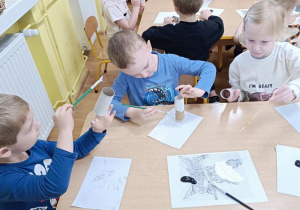 Dzieci malują rolki po papierze.