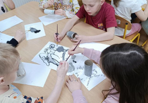 Dzieci malują rolki po papierze.