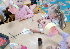 Dzieci sklejają koszyczki i kończą pracę z zajączkami.