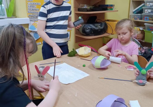 Dzieci sklejają koszyczki i kończą pracę z zajączkami.