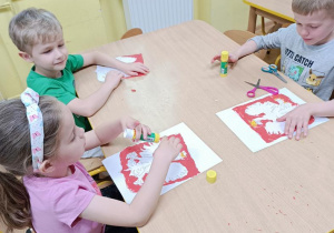 Dzieci wyklejają plasteliną godło Polski.