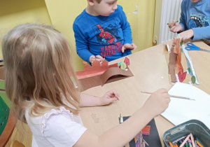 Dzieci wycinają, wypychają i sklejają zamek.