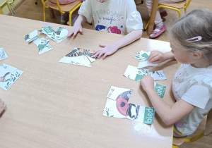 Dzieci składają puzzle ze zwierzętami zamieszkującymi łąkę.
