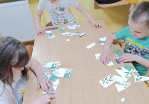 Dzieci składają puzzle ze zwierzętami zamieszkującymi łąkę.