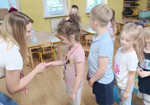 Pani wręcza dzieciom medale.