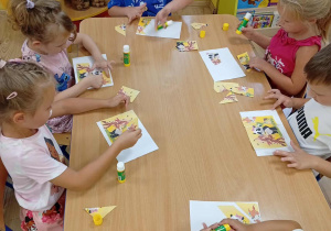 Dzieci układają i przyklejają puzzle.