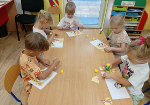 Dzieci układają i przyklejają puzzle.