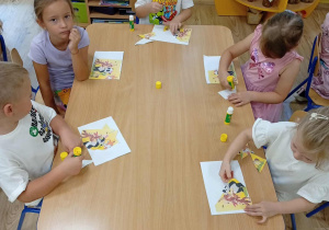 Dzieci układają i przyklejają puzzle.