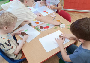Dzieci stemplują liście tworząc z nich jesienne drzewa.