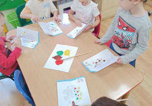 Dzieci wykonują jesienne drzewo odbijając pomalowaną część.