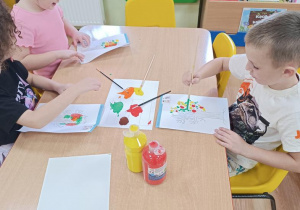 Dzieci wykonują jesienne drzewo odbijając pomalowaną część.